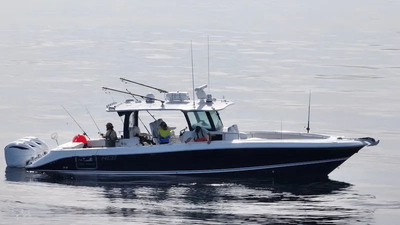 Slide: The Image of A 2023 HCB 42 Lujo on calm water. Several people are on board, some are fishing. - 7
