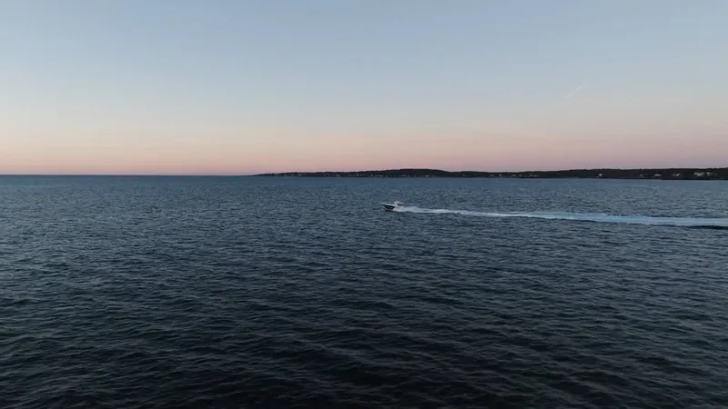 Slide: The Image of An HCB 42 Lujo boat speeds across the calm sea at sunset. - 14