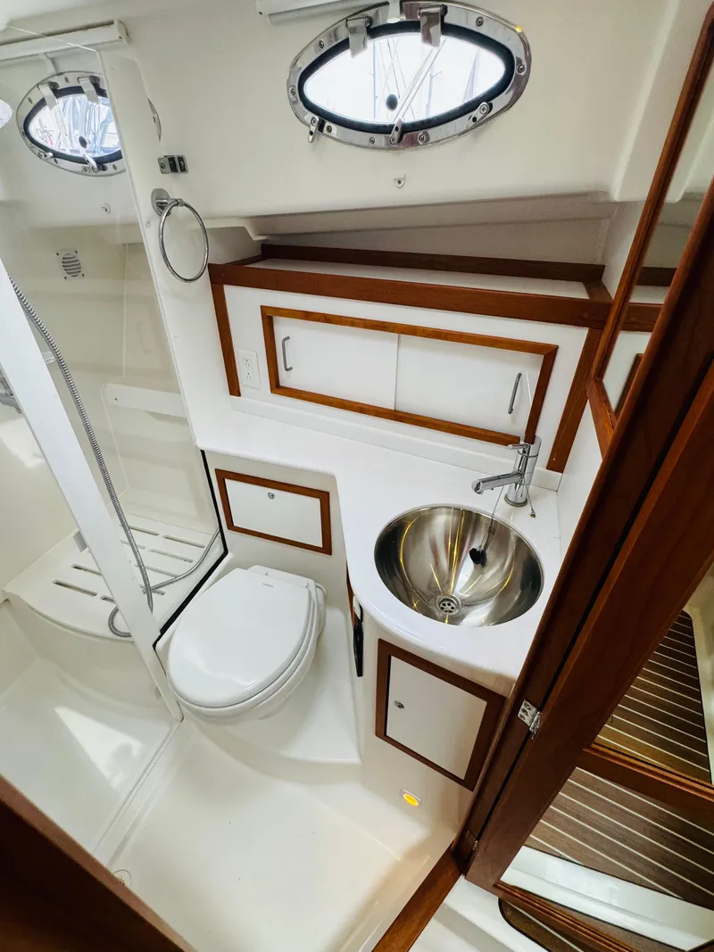 Slide: The Image of The image shows a sleek boat bathroom with a sink, toilet, and wood paneling. - 37