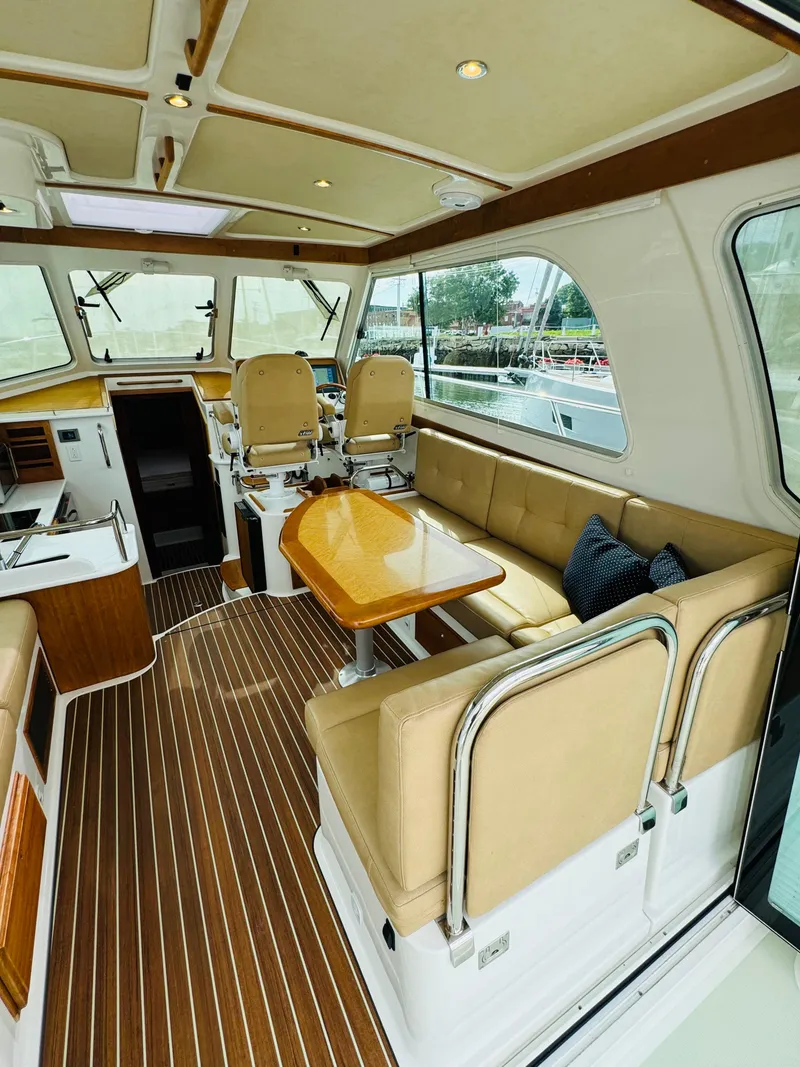 Slide: The Image of Interior of a 2018 Back Cove 37 with beige seating and a wooden table. - 25
