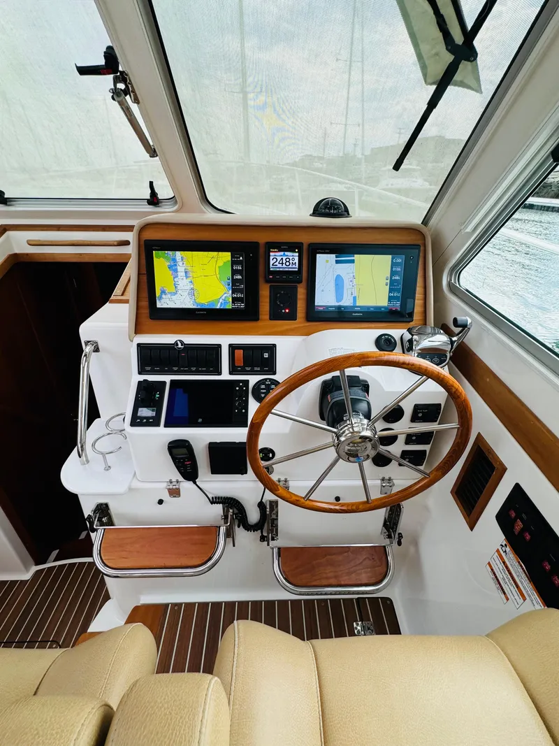 Slide: The Image of The cockpit of a 2018 Back Cove 37 features a sleek steering wheel and modern navigation equipment. - 47