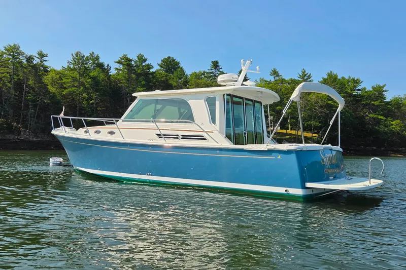 Slide: The Image of 2018 Back Cove 37 boat on calm water, surrounded by lush trees. - 13