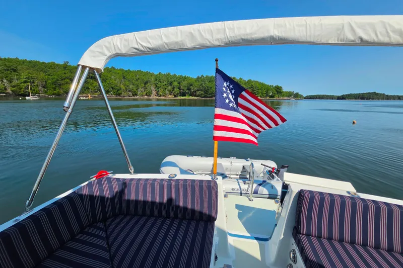 Slide: The Image of 2018 Back Cove 37 boat with American flag on calm lake, surrounded by lush greenery. - 97