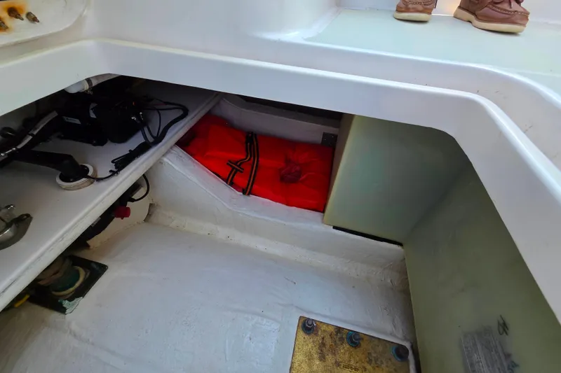 Slide: The Image of 2018 Back Cove 37 boat storage compartment with red life jacket and mechanical components. - 89