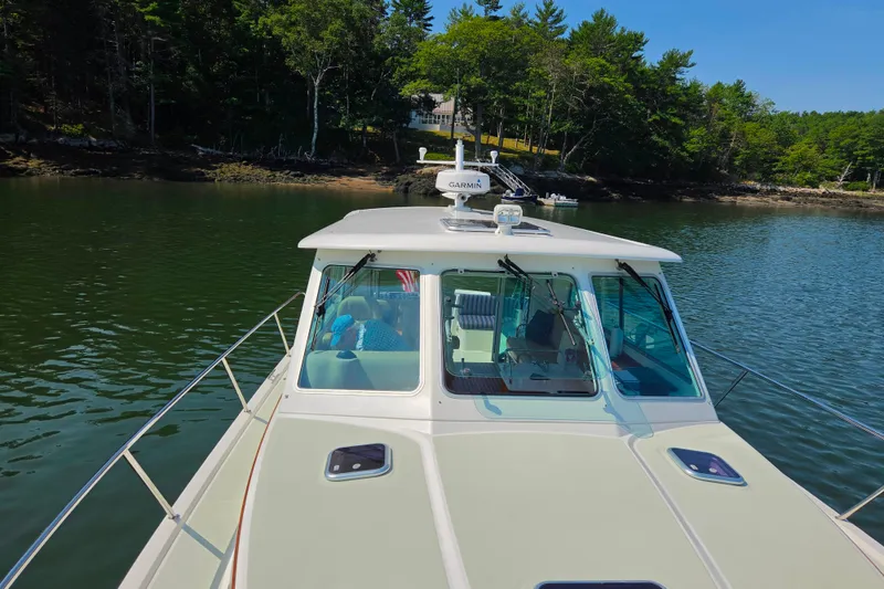 Slide: The Image of 2018 Back Cove 37 boat on calm water near a wooded shoreline. - 18