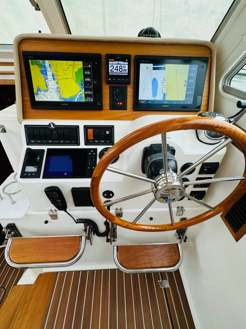 Slide: The Image of The cockpit of a 2018 Back Cove 37 features a sleek wooden wheel and modern navigation equipment. - 46