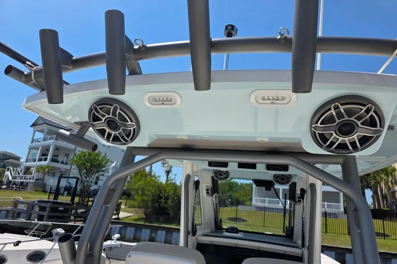 Slide: The Image of 2023 Solace 32CS boat with speakers and rod holders, docked near waterfront homes. - 17