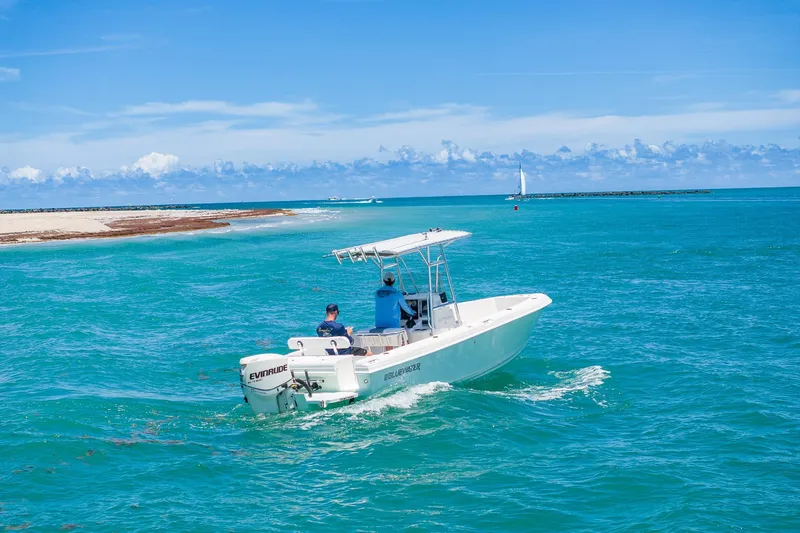 Slide: The Image of 2006 Bluewater 2150 CC boat cruising in turquoise ocean near sandy shore. - 3