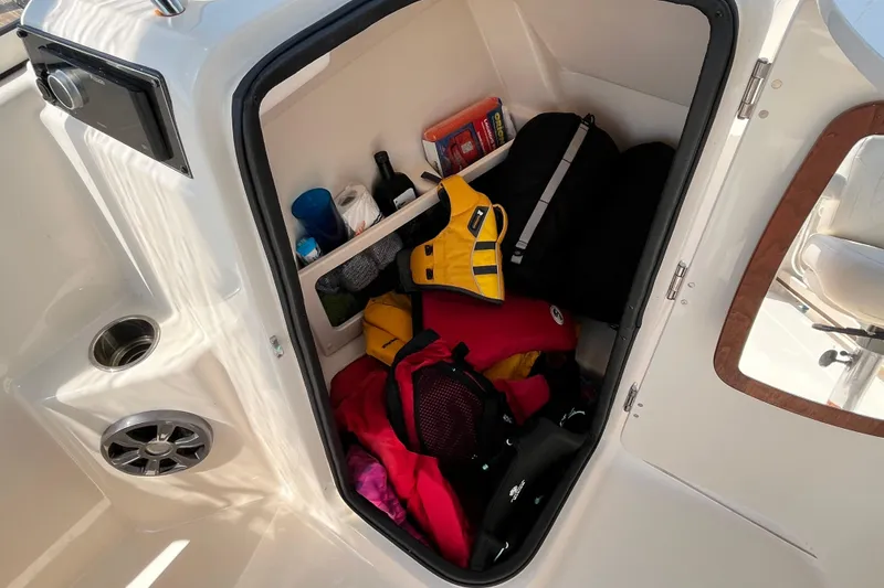 Slide: The Image of Storage compartment in 2021 Grady-White Freedom 215 boat, filled with life jackets and gear. - 22