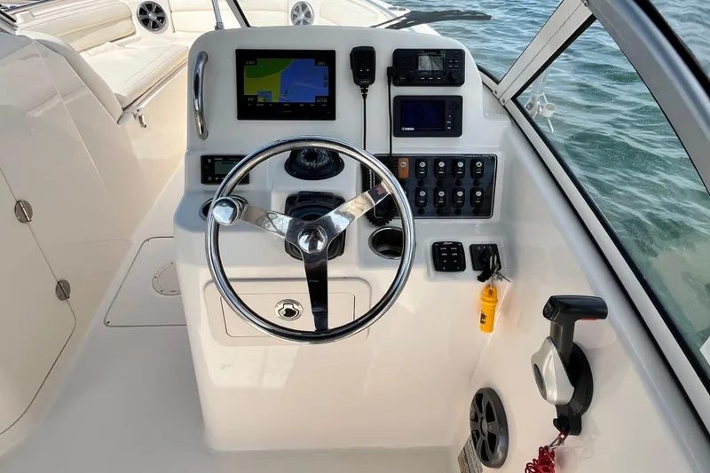 Slide: The Image of 2021 Grady-White Freedom 215 boat dashboard with steering wheel and navigation controls. - 18