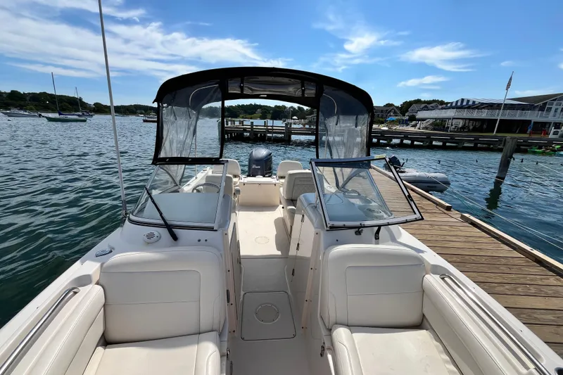 Slide: The Image of 2021 Grady-White Freedom 215 boat docked, showcasing spacious seating and clear canopy under a sunny sky. - 28