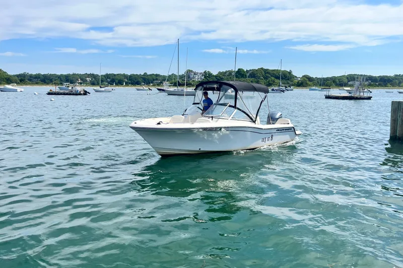 Slide: The Image of 2021 Grady-White Freedom 215 boat cruising on a scenic lake with other boats. - 6