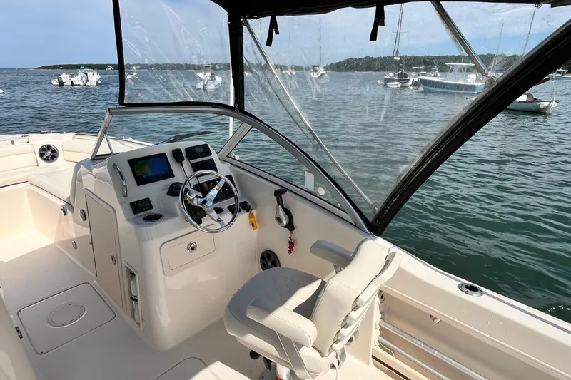 Slide: The Image of 2021 Grady-White Freedom 215 boat interior with steering wheel and dashboard, docked on calm water. - 16