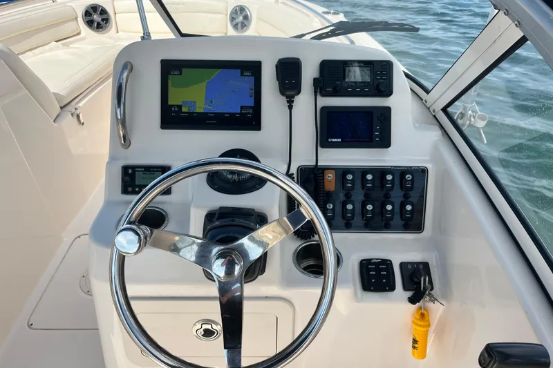 Slide: The Image of 2021 Grady-White Freedom 215 boat dashboard with steering wheel and navigation controls. - 19
