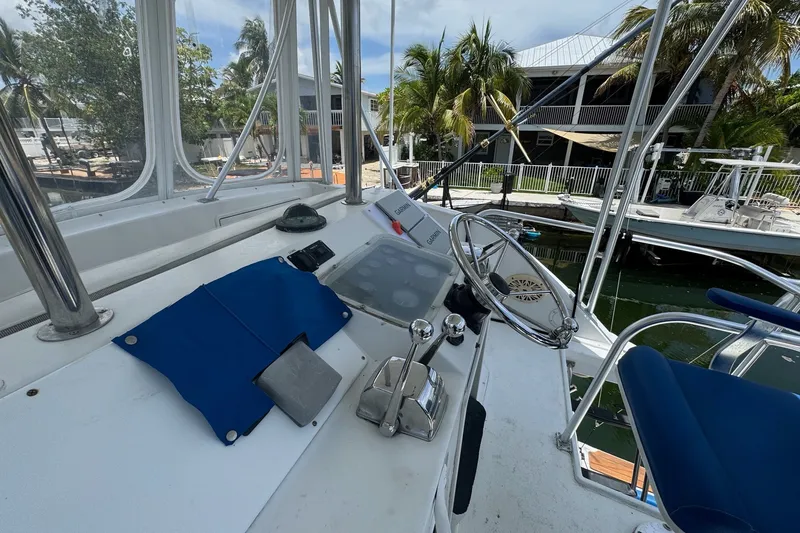 Slide: The Image of Helm of 1991 Ocean Yachts 35 Super Sport with steering wheel and controls, docked near palm trees. - 18