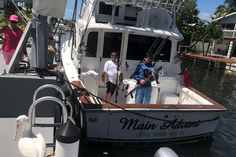 Slide: The Image of 1991 Ocean Yachts 35 Super Sport docked, people holding fish, "Main Advent" boat name visible. - 3