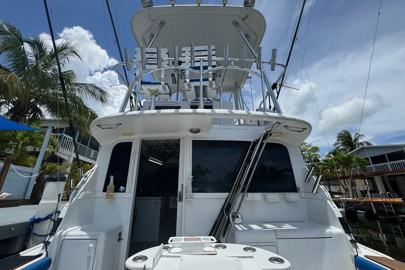 Slide: The Image of 1991 Ocean Yachts 35 Super Sport boat docked, featuring fishing equipment and tropical surroundings. - 9