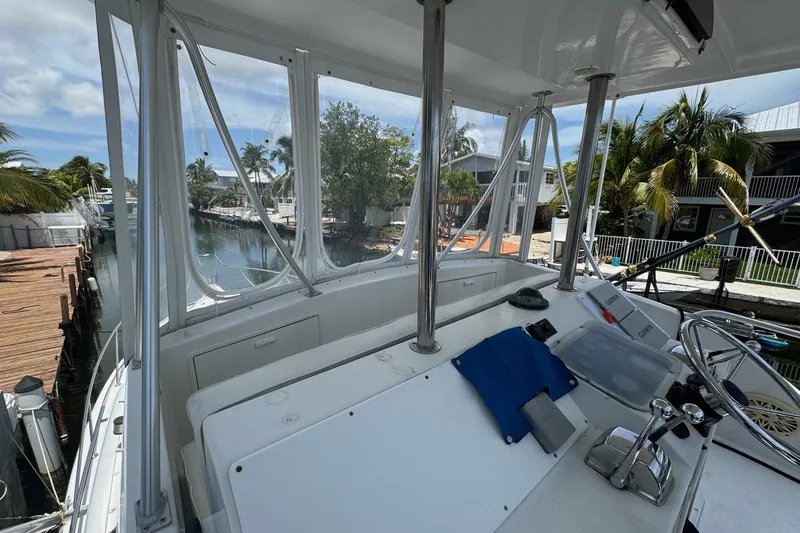 Slide: The Image of 1991 Ocean Yachts 35 Super Sport cockpit with helm, docked near palm trees and waterfront homes. - 21