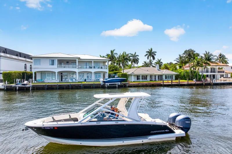 Slide: The Image of 2023 Chaparral 280 OSX boat cruising on a sunny waterfront with luxury homes in the background. - 4