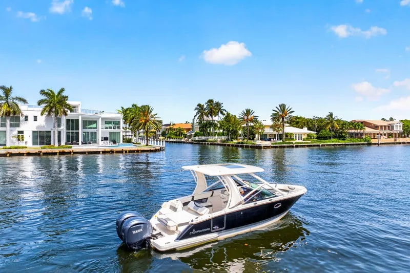 Slide: The Image of 2023 Chaparral 280 OSX boat cruising on a sunny waterfront with luxury homes. - 7