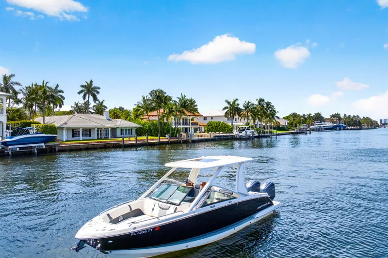 Slide: The Image of 2023 Chaparral 280 OSX boat cruising on a sunny waterfront with palm trees. - 5