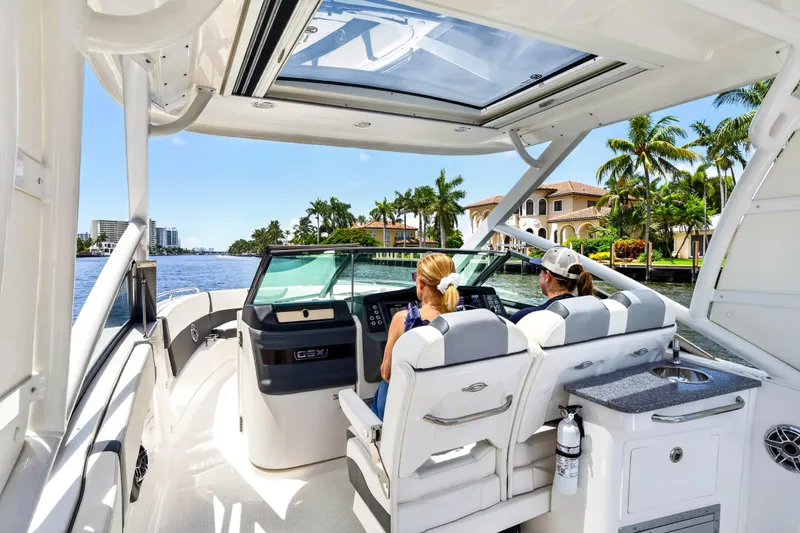 Slide: The Image of 2023 Chaparral 280 OSX boat interior with two people navigating on a sunny day. - 80