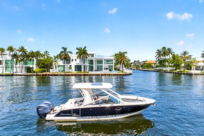 Slide: The Image of 2023 Chaparral 280 OSX boat cruising on a sunny waterfront with palm trees. - 6