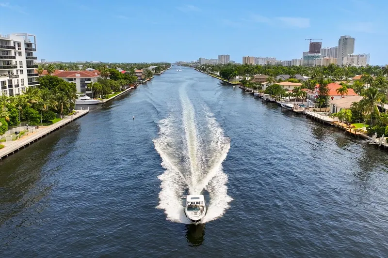 Slide: The Image of 2023 Chaparral 280 OSX cruising on a scenic canal with waterfront homes and city skyline. - 9