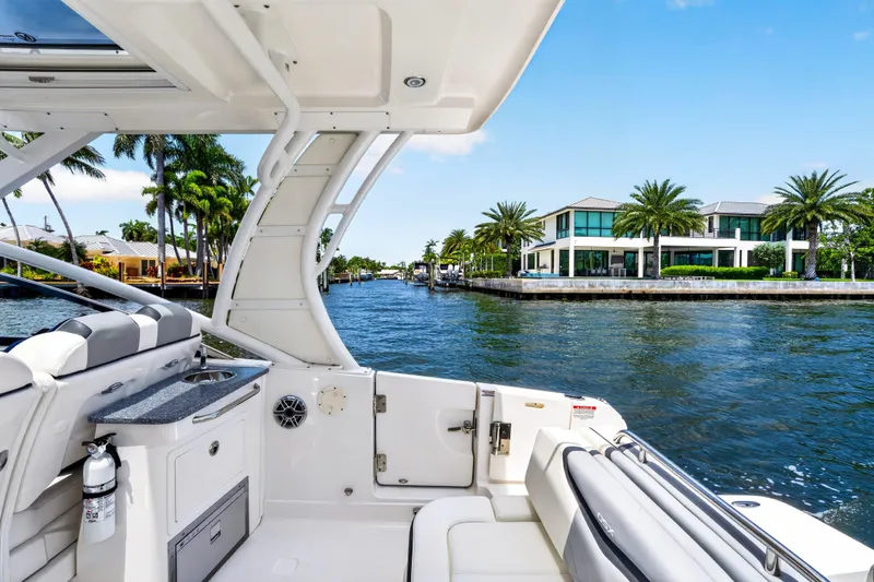 Slide: The Image of 2023 Chaparral 280 OSX boat cruising near waterfront homes with palm trees. - 70