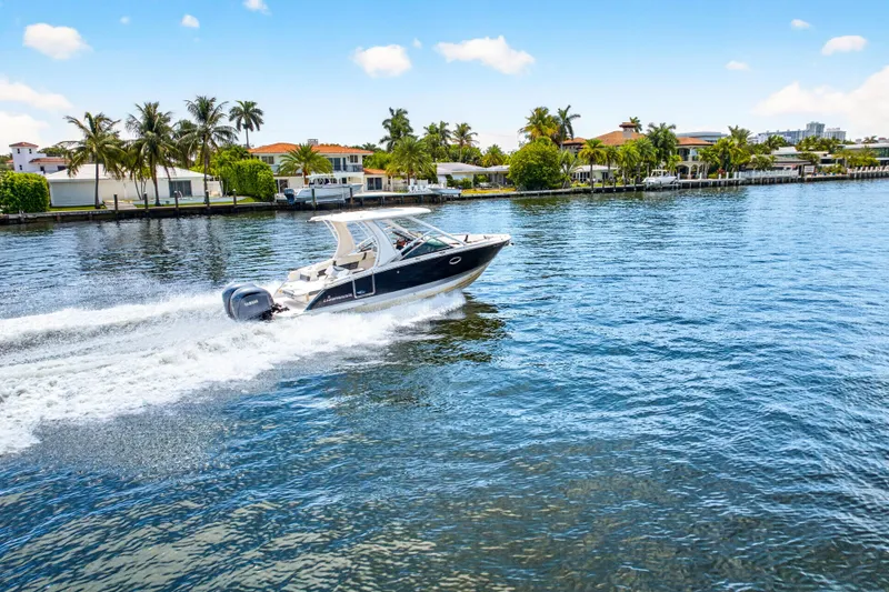 Slide: The Image of 2023 Chaparral 280 OSX cruising on a sunny waterfront with palm trees. - 1