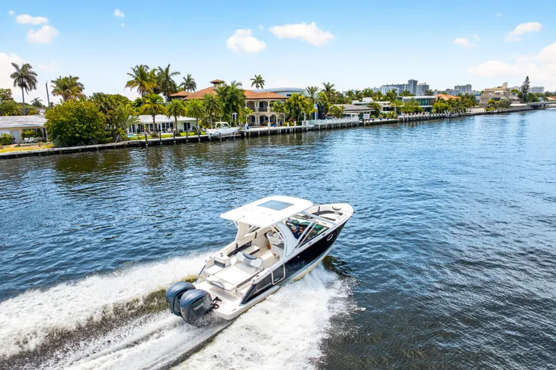 Slide: The Image of 2023 Chaparral 280 OSX cruising on a scenic waterway with waterfront homes. - 0