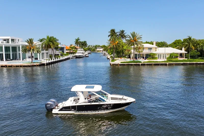 Slide: The Image of 2023 Chaparral 280 OSX boat cruising on a scenic waterfront with luxury homes. - 13