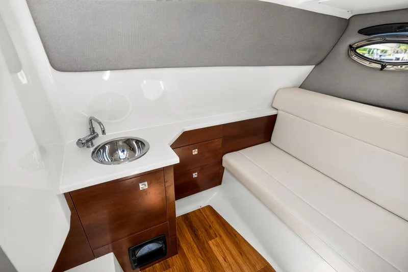 Slide: The Image of 2023 Chaparral 280 OSX cabin interior with sink, seating, and wood accents. - 38