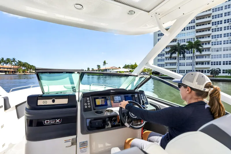 Slide: The Image of Person steering 2023 Chaparral 280 OSX boat on a sunny day near waterfront buildings. - 45
