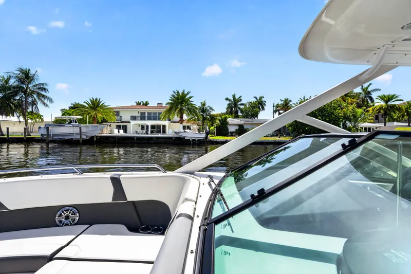 Slide: The Image of 2023 Chaparral 280 OSX boat cruising near waterfront homes with palm trees. - 35