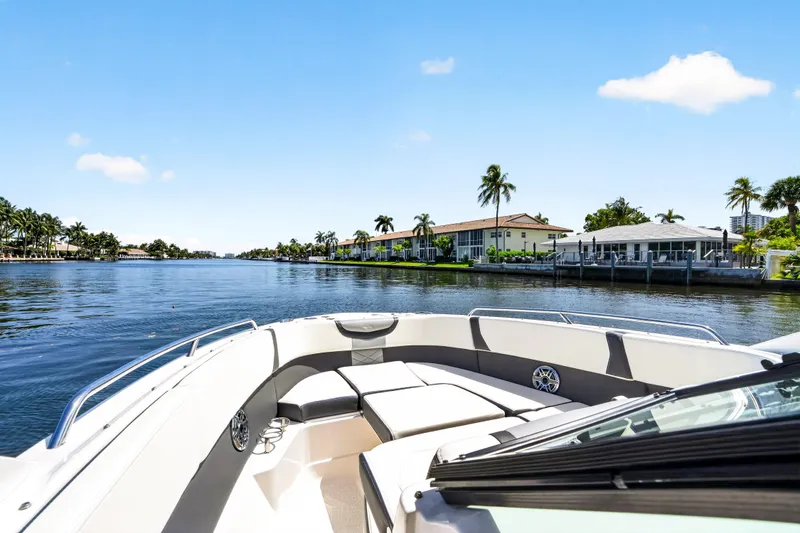 Slide: The Image of 2023 Chaparral 280 OSX boat cruising on a scenic waterfront with palm trees. - 37