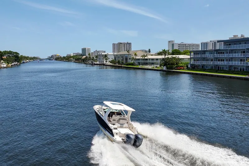 Slide: The Image of 2023 Chaparral 280 OSX cruising on a scenic waterway with cityscape backdrop. - 11