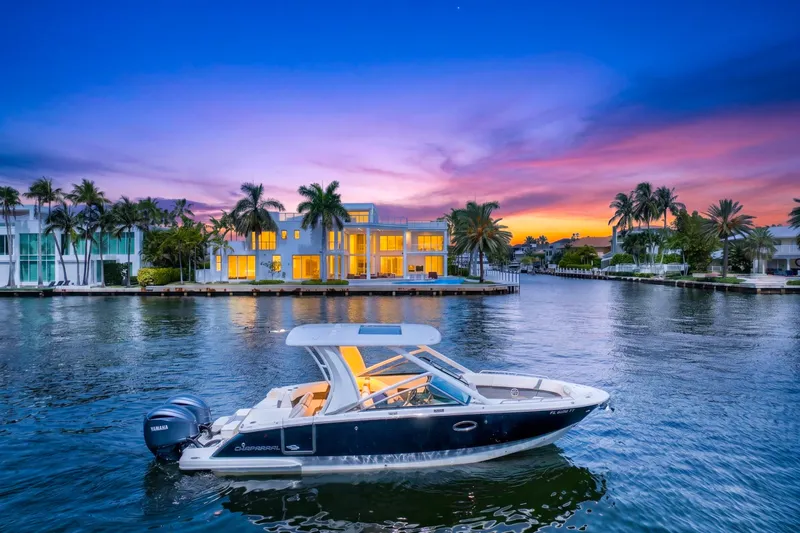 Slide: The Image of 2023 Chaparral 280 OSX boat on serene water at sunset, luxury waterfront homes in background. - 83