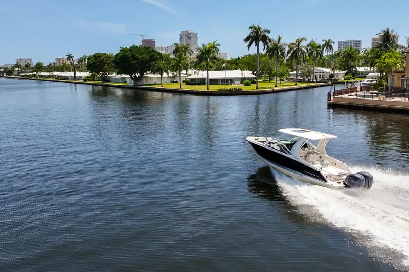 Slide: The Image of 2023 Chaparral 280 OSX cruising on a scenic waterway with palm trees and cityscape. - 12