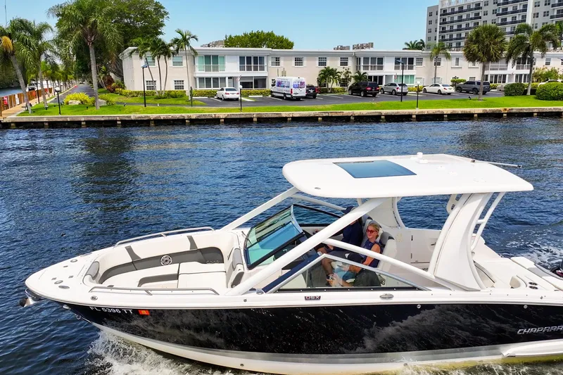 Slide: The Image of 2023 Chaparral 280 OSX boat cruising on a sunny waterfront with palm trees. - 8