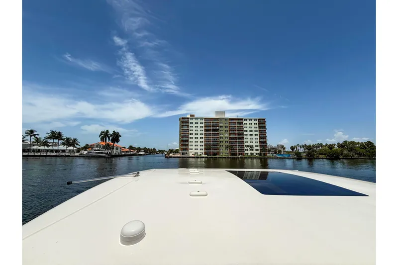 Slide: The Image of 2023 Chaparral 280 OSX boat cruising near waterfront buildings under a clear blue sky. - 81