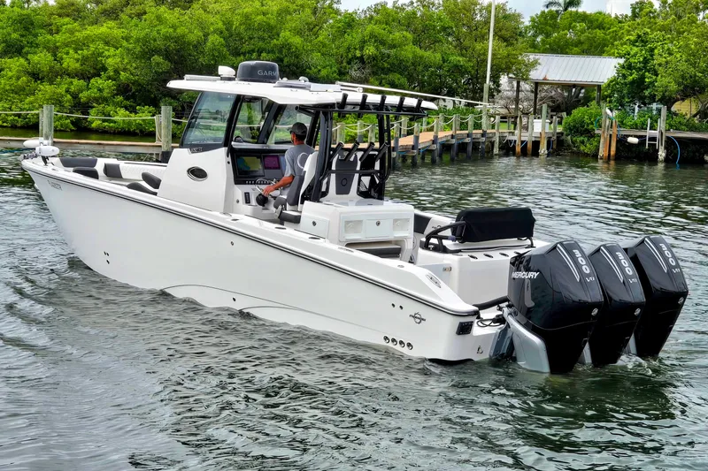 The Image of 2024 Fountain 32 NX Sportfish boat with triple Mercury engines on a calm waterway. - 0