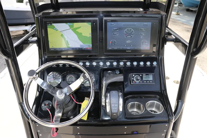 Slide: The Image of Control panel of a 2018 ShearWater 25 LTZ boat with navigation screens and steering wheel. - 23