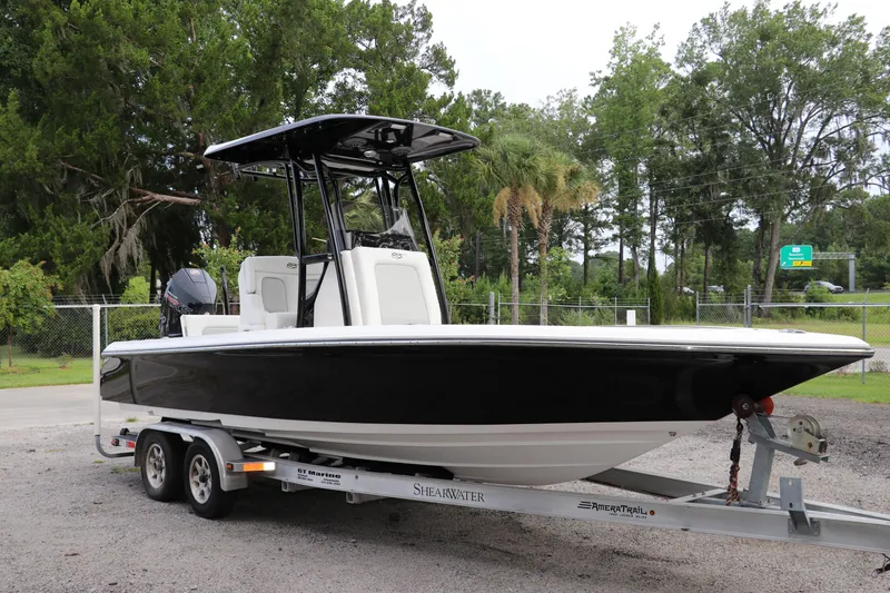 Slide: The Image of 2018 ShearWater 25 LTZ boat on trailer, surrounded by lush greenery. - 1