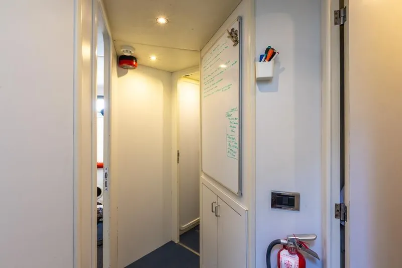 Slide: The Image of Hallway inside 2000 Azimut 85 Ultimate yacht, featuring whiteboard and fire extinguisher. - 31