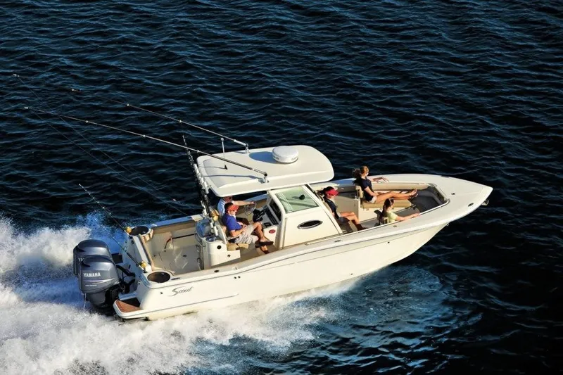 Slide: The Image of A 2020 Scout 277 LXF boat speeds across the water with several people on board. - 1