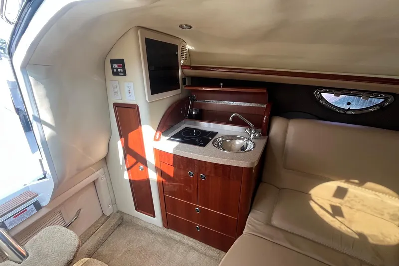 Slide: The Image of Interior of a 2008 Cobalt 323 boat featuring a compact kitchenette and seating area. - 27