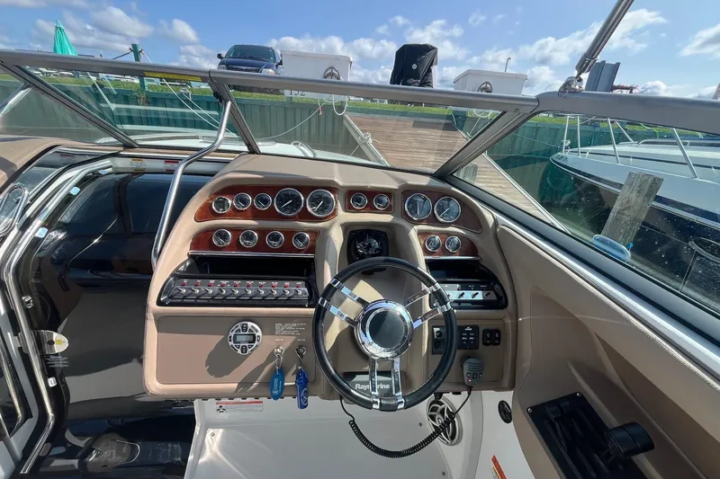 Slide: The Image of 2008 Cobalt 323 boat dashboard with steering wheel and instrument panel, docked under a sunny sky. - 19