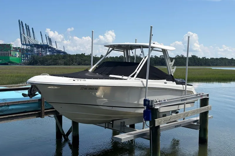 Slide: The Image of 2022 Boston Whaler 240 Vantage boat on lift, docked near industrial port. - 6