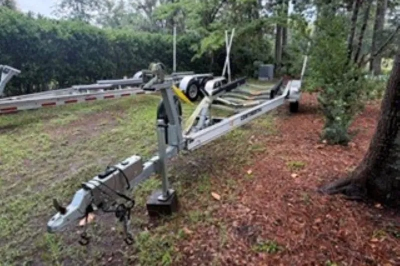 Slide: The Image of Boat trailer for 2022 Boston Whaler 240 Vantage, parked on grassy area with trees. - 28